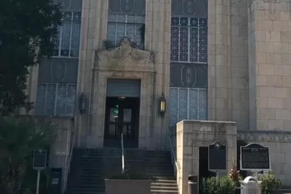 Exterior of a courthouse with stairs, large windows, and decorative stonework.